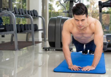 Genç adam vücut geliştirmeci fitness merkezinde itmek.