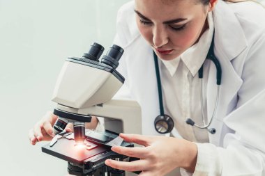 Hastane laboratuvarında mikroskop kullanan doktor.