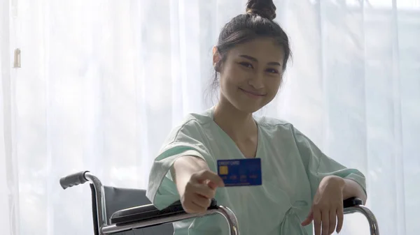Felice paziente tenere la carta di credito e sorridere mentre seduto su wheelc — Foto Stock