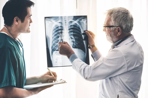 Dolgozó orvosok a röntgen-film a beteg mellkasi. — Stock Fotó