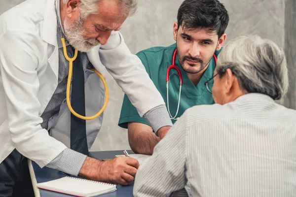 Mannelijke arts team praten met senior patiënt bezoek — Stockfoto