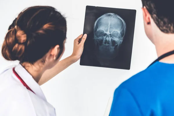 Médicos que trabajan con radiografías de la cabeza del paciente . — Foto de Stock