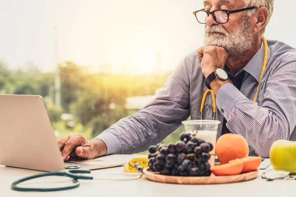 Senior médico nutricionista masculino que trabaja en el ordenador portátil . —  Fotos de Stock