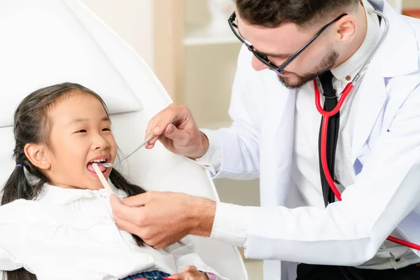 Dentista examinando dientes infantiles en clínica dental . — Foto de Stock