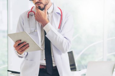 Hastanede tablet bilgisayar üzerinde çalışan doktor.