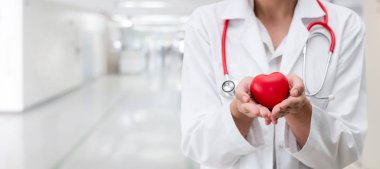 Hastane ofisinde kırmızı kalp tutan doktor.