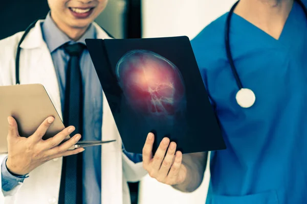 Médicos que trabajan con radiografías de la cabeza del paciente . — Foto de Stock