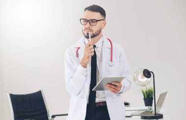 Hastanede tablet bilgisayar üzerinde çalışan doktor.