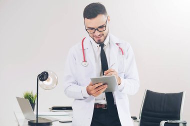 Hastanede tablet bilgisayar üzerinde çalışan doktor.