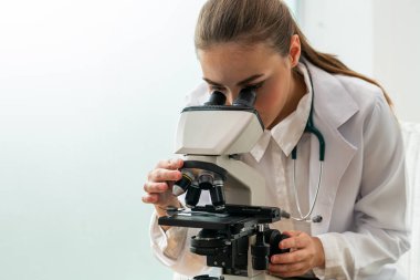 Hastane laboratuvarında mikroskop kullanan doktor.