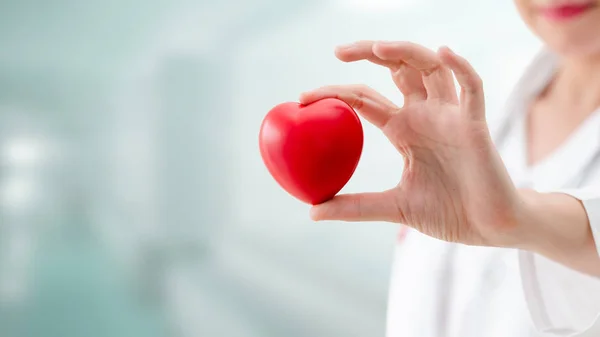 Doctor sosteniendo un corazón rojo en la oficina del hospital . — Foto de Stock