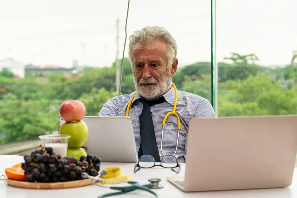 Senior médico nutricionista masculino que trabaja en el ordenador portátil . —  Fotos de Stock