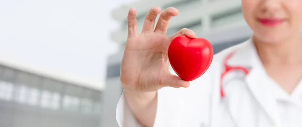 Doctor sosteniendo un corazón rojo en la oficina del hospital . — Foto de Stock