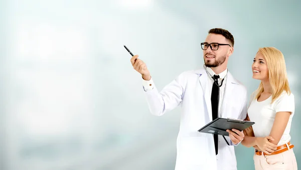 Doctor with patient pointing at empty copy space.