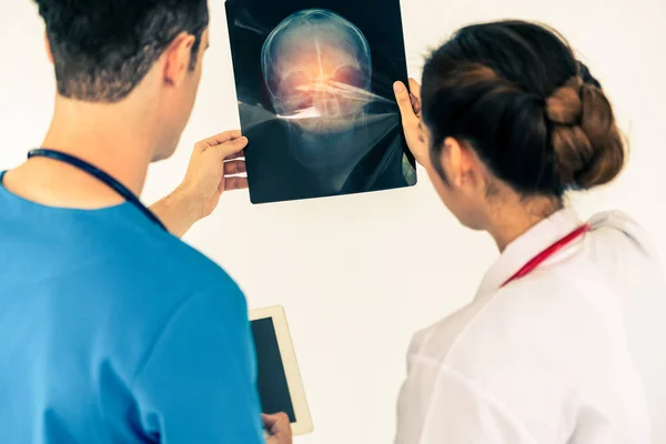Lekarze pracujący z filmem rentgenowskim głowy pacjenta. — Zdjęcie stockowe