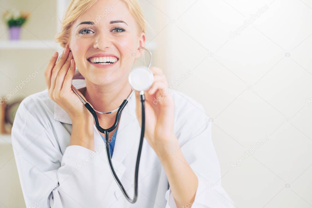Female doctor pointing stethoscope at blank space.