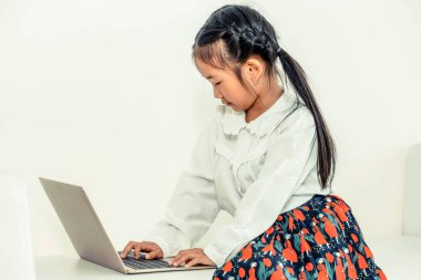 Küçük çocuk beyaz kanepeüzerinde dizüstü bilgisayar kullanarak.