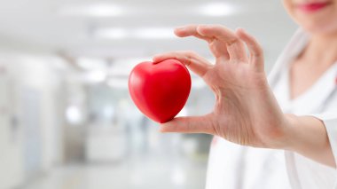 Hastane ofisinde kırmızı kalp tutan doktor.