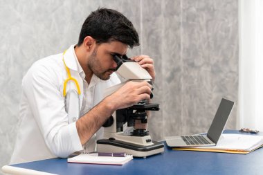 Hastane laboratuvarında mikroskop kullanan doktor.