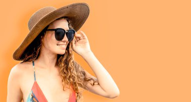 Renkli arka planda poz veren mayolu kadın.