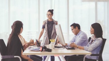 Kıdemli lider takım üyelerine tavsiye konuşması yapıyor. Modern ofisteki masada yaratıcı iş adamları buluşuyor. Çok kültürlü iş ekibi..