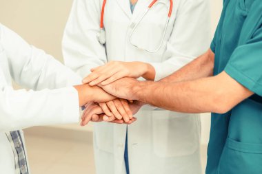 Doktor, cerrah ve hemşire el ele tutuşuyor.