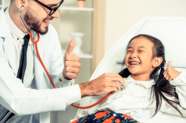 Doktor hastanede küçük mutlu çocuk muayene.