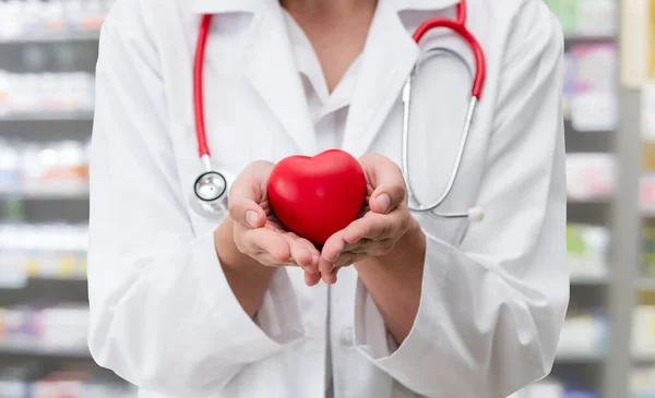 Doctor sosteniendo un corazón rojo en la oficina del hospital . —  Fotos de Stock