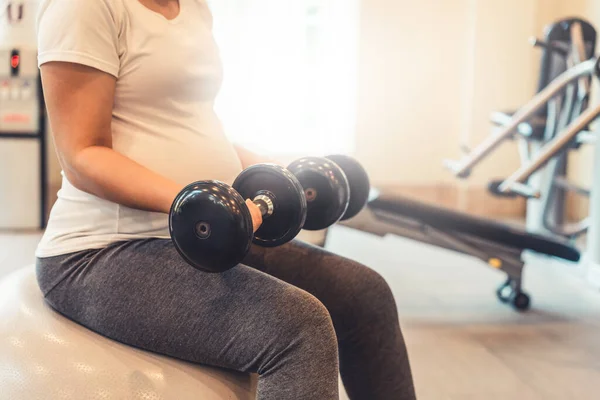 Active pregnant woman exercise in fitness center.