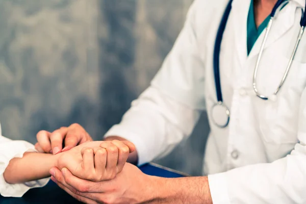 Jovem médico examinando paciente em consultório hospitalar . — Fotografia de Stock