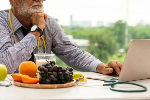 Senior médico nutricionista masculino que trabaja en el ordenador portátil . —  Fotos de Stock