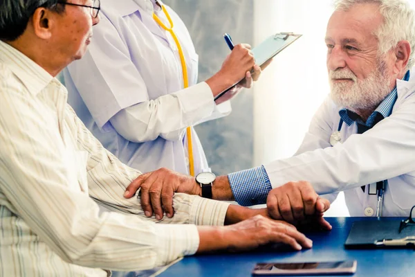 Senior male doctor talking to elder man patient in the hospital office. Medical healthcare and doctor staff service concept.