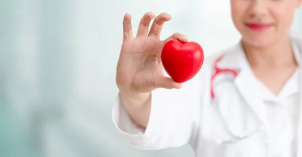 Lekarz posiadający czerwone serce w biurze szpitala. — Zdjęcie stockowe