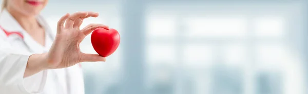 Doctor sosteniendo un corazón rojo en la oficina del hospital . — Foto de Stock