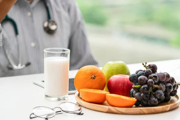 Senior male nutritionist doctor working at desk.