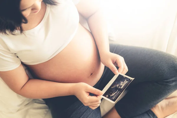 Mujer embarazada feliz y esperando un bebé en casa. — Foto de Stock