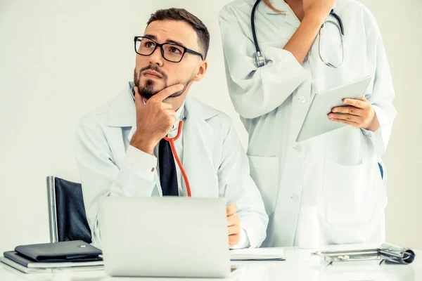 El médico en el hospital trabaja en el ordenador con el socio . — Foto de Stock