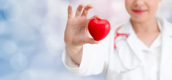 Doctor sosteniendo un corazón rojo en la oficina del hospital . —  Fotos de Stock