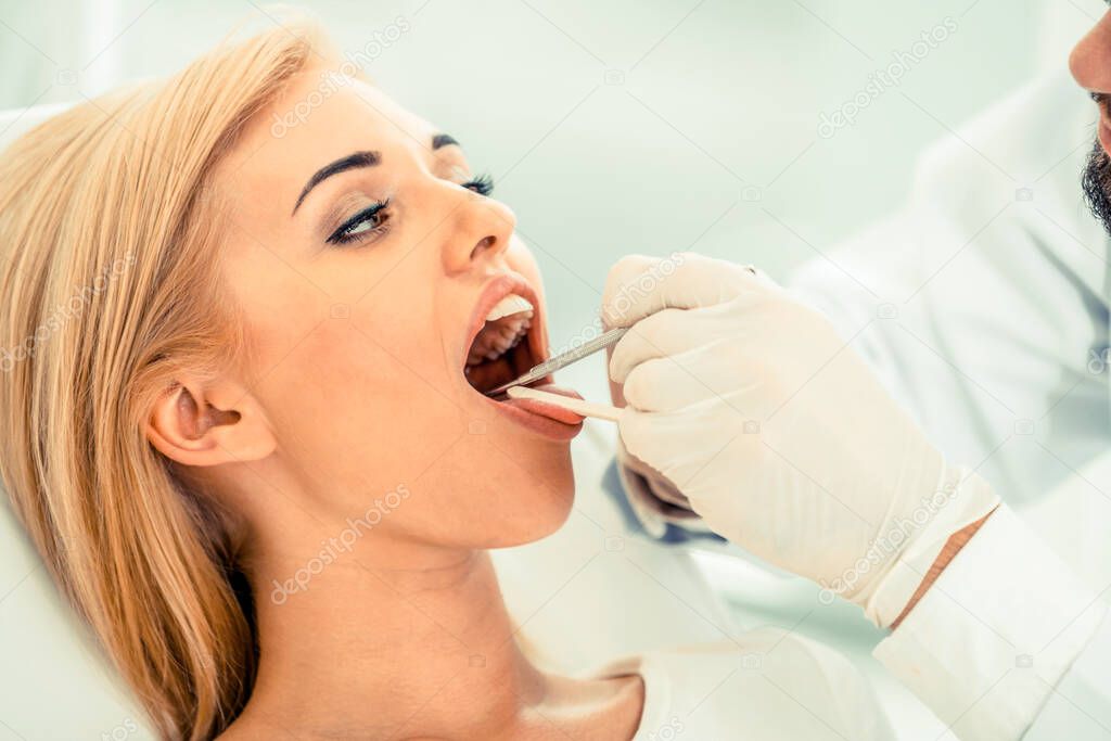 Young dentist examining patient in dental clinic.