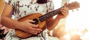 Stüdyoda ukulele çalan mutlu kadın müzisyen.