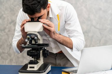 Hastane laboratuvarında mikroskop kullanan doktor.