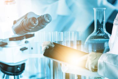 Araştırma ve geliştirme konsepti. Tıp çalışması için laboratuvarda mikrobiyoloji ve kimya için bilimsel ve tıbbi laboratuvar aleti, mikroskop, test tüpü ve cam şişesinin çift pozlama görüntüsü.