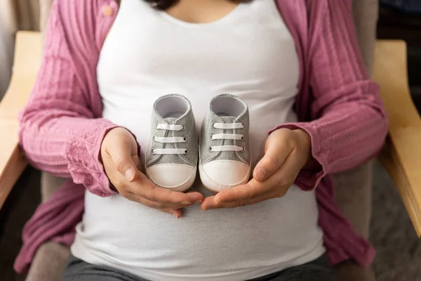 Mujer Embarazada Sintiéndose Feliz Casa Mientras Sostiene Zapatos Pequeños — Foto de Stock