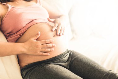 Hamile bir kadın müstakbel çocuğuna bakarken kendini mutlu hissediyor. Doğum öncesi bakım ve kadın hamileliği konsepti.