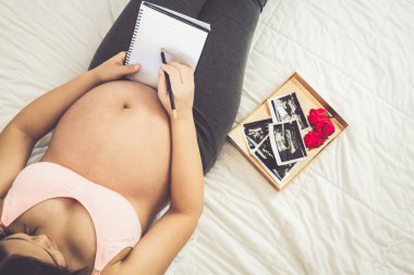 Hamile bir kadın müstakbel çocuğuna bakarken kendini mutlu hissediyor. Doğum öncesi bakım ve kadın hamileliği konsepti.