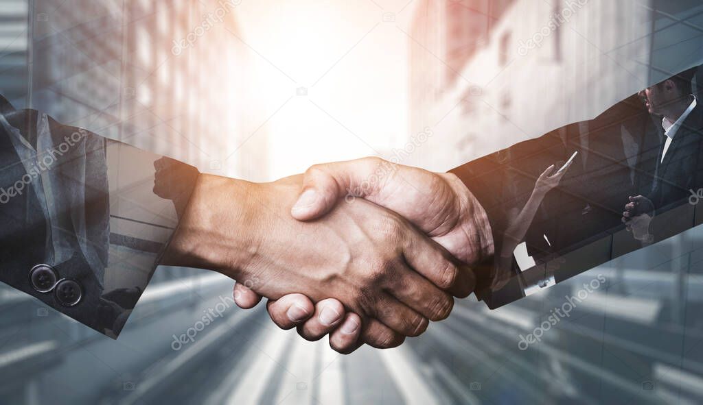 Double exposure image of business people handshake on city office building in background showing partnership success of business deal. Concept of corporate teamwork, trust partner and work agreement.