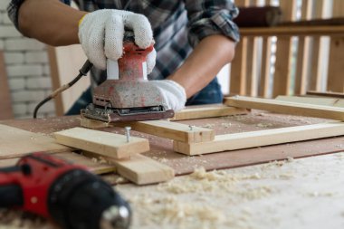 Marangoz atölyede ahşap işçiliği yapıyor. İnşaat malzemesi ya da ahşap mobilya üretiyor. Genç Asyalı marangoz zanaat için profesyonel araçlar kullanır. DIY üreticisi ve marangozluk konsepti.