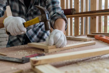 Marangoz atölyede ahşap işçiliği yapıyor. İnşaat malzemesi ya da ahşap mobilya üretiyor. Genç Asyalı marangoz zanaat için profesyonel araçlar kullanır. DIY üreticisi ve marangozluk konsepti.