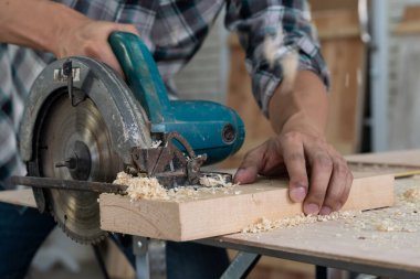 Marangoz atölyede ahşap işçiliği yapıyor. İnşaat malzemesi ya da ahşap mobilya üretiyor. Genç Asyalı marangoz zanaat için profesyonel araçlar kullanır. DIY üreticisi ve marangozluk konsepti.