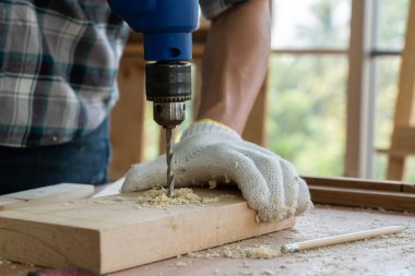 Marangoz atölyede ahşap işçiliği yapıyor. İnşaat malzemesi ya da ahşap mobilya üretiyor. Genç Asyalı marangoz zanaat için profesyonel araçlar kullanır. DIY üreticisi ve marangozluk konsepti.